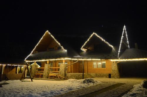 a log cabin with christmas lights on it at Sadyba Pikuy in Bilasovytsya