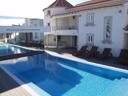 a large swimming pool in front of a house at Quinta Do Molinu in Lourinhã