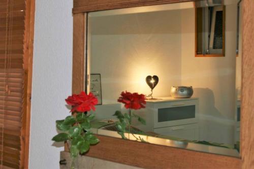 a mirror with a vase with red flowers and a television at Gemütliches großzügiges Apartment in Höhr-Grenzhausen