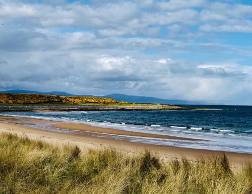 a sandy beach with the ocean and mountains in the background at Albatross B&B Dornoch in Dornoch