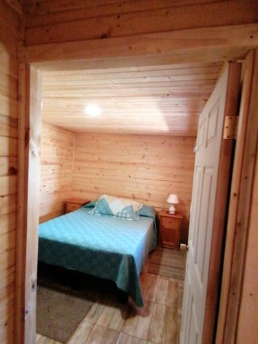 1 dormitorio con 1 cama en una cabaña de madera en Cabaña sol y luna en El Quisco