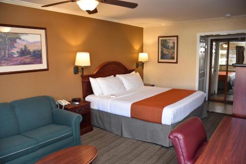 a hotel room with a bed and a couch and a chair at Dynasty Suites Redlands in Redlands