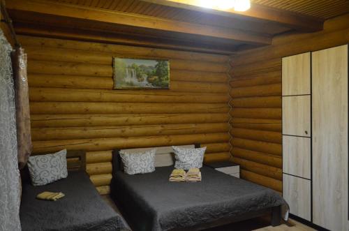 a room with two beds in a log cabin at Sadyba Pikuy in Bilasovytsya