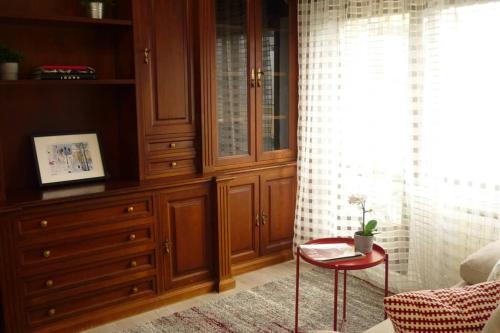 un dormitorio con armarios de madera y una mesa roja en una habitación en ÁTICO AUDITORIO disfrute sus 40 metros de terraza orientada al sur en Oviedo
