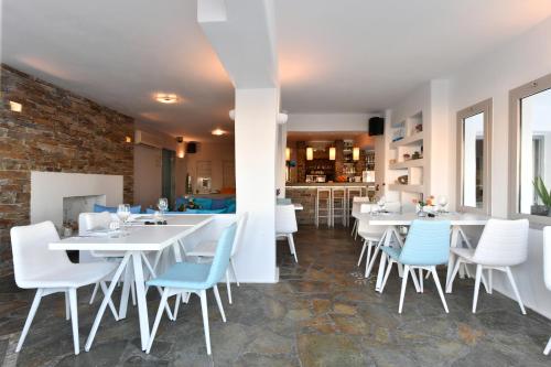 a restaurant with white tables and blue chairs at Kanale's Rooms & Suites in Naousa