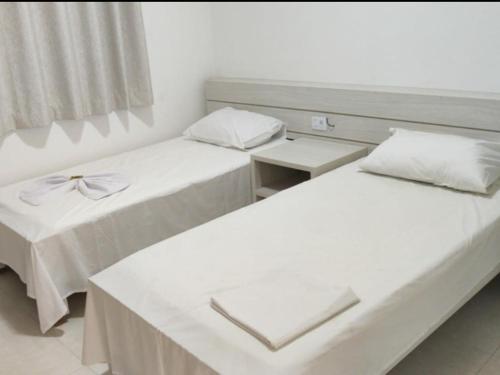 two beds in a room with white walls at Nico Palace Hotel in Guanambi
