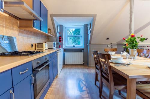 a kitchen with blue cabinets and a wooden table at 4 Still Brae in Tarbet
