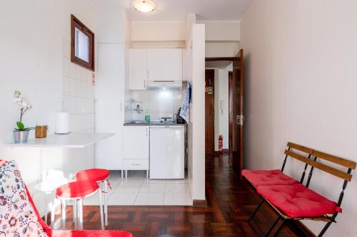 a living room with red chairs and a kitchen at Cozy Apartment Alegria Balcony in Porto