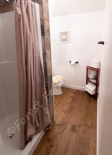 a bathroom with a shower curtain and a wooden floor at The Surf Lodge and Pub in Gabriola
