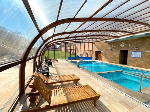 a swimming pool with wooden benches and a large glass ceiling at VISTA AZUL - Punta Prima - SPA y Piscina in Torrevieja