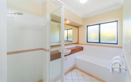 a bathroom with a tub and a sink at Oceania Cottage - LJHooker Yamba in Yamba