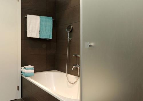 a bathroom with a tub and a shower with blue towels at Apartment Superior Parrot in Zermatt