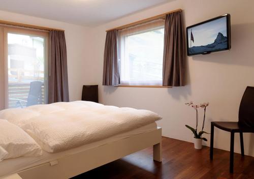 - une chambre avec un lit et une télévision murale dans l'établissement Apartment Superior Parrot, à Zermatt