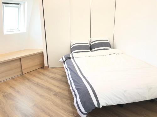 a bed in a room with white walls and wooden floors at Studio neuf et cosy au centre de Paris in Paris