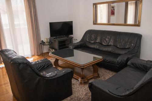 a living room with black leather furniture and a table at Apartman Miletic in Mostar
