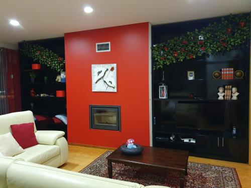 a living room with a red wall with a couch and a clock at Apartamento T3-S.PedroII in Ponta Delgada