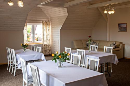 una habitación con mesas blancas y sillas con flores. en Agroturystyka u Jarka, en Bryzgiel