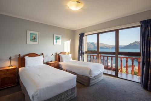 a hotel room with two beds and a balcony at Matterhorn Lodge in Queenstown