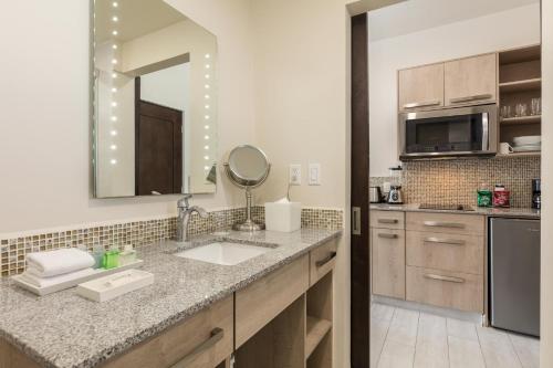 a kitchen with a sink and a mirror at Medano Hotel and Spa in Cabo San Lucas