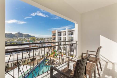 a balcony with two chairs and a view of a city at Medano Hotel and Spa in Cabo San Lucas