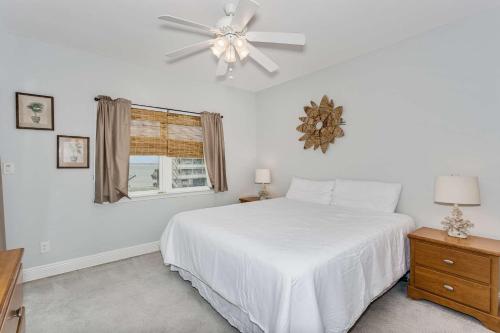 a bedroom with a white bed and a ceiling fan at Baywatch A8 in Pensacola Beach