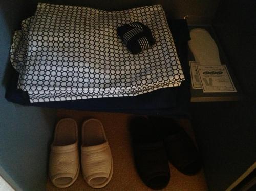 a bedroom with a bed and some shoes and a magazine at Pension Ohno in Sobetsu