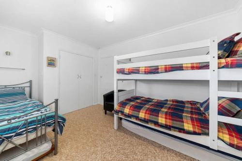 a bedroom with two bunk beds and a bed at Calapso Cottage - Waikanae Beach Holiday Home in Waikanae