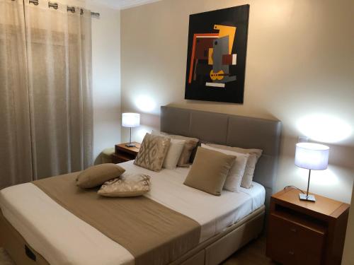 a bedroom with a bed with two lamps and a painting at Galerias 90 in Pombal