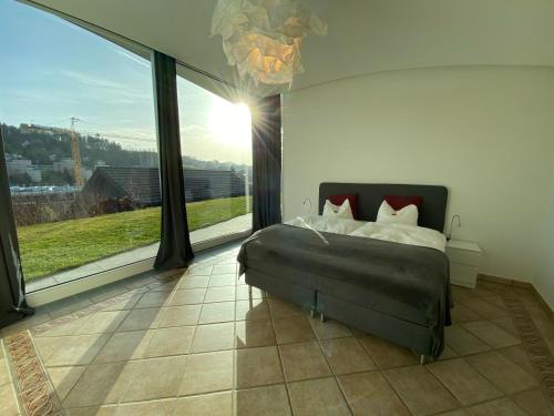 a bedroom with a bed and a large window at Exklusive Mini-Villa mit viel Platz in Herisau