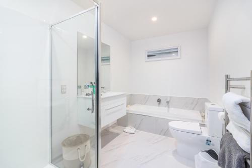 a white bathroom with a shower and a toilet at Restful in Riccarton - Christchurch in Christchurch