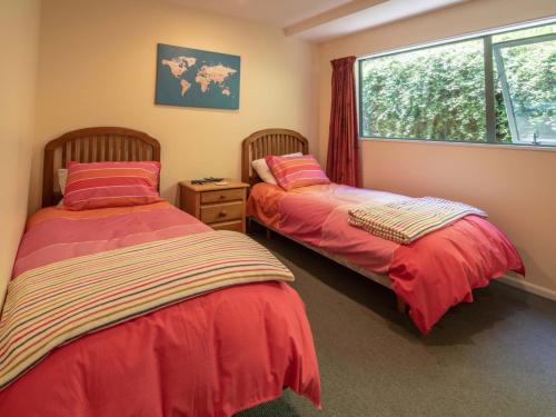 two beds in a room with a window at Rue Noyer Lookout - Akaroa Holiday Home in Akaroa
