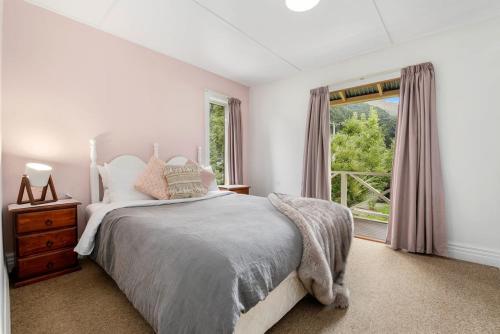 a white bedroom with a bed and a window at Central Peach - Queenstown Holiday Home in Queenstown