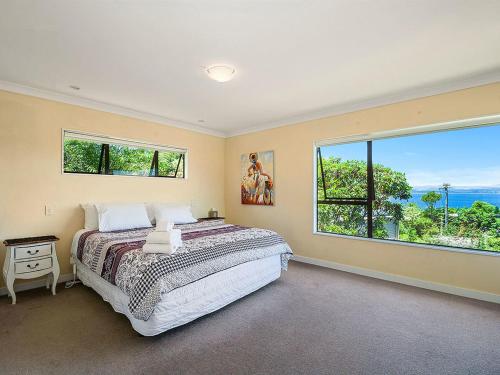 een slaapkamer met een groot bed en een groot raam bij Acacia Bay Getaway - Lake Taupo Holiday Home in Taupo