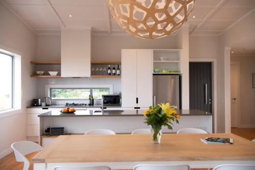 a kitchen with a wooden table and a vase of flowers at Waimarama Heights - Waimarama Holiday Home in Waimarama