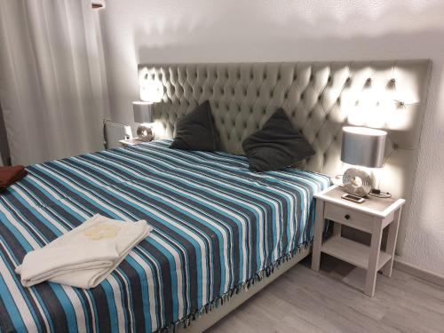 1 dormitorio con 1 cama grande con manta de rayas azul y blanco en Apartment Qiu, en Costa da Caparica