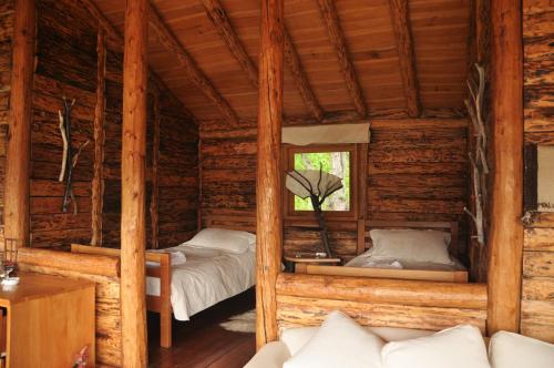 two beds in a log cabin with a window at Mallin Colorado Ecolodge in Aldana