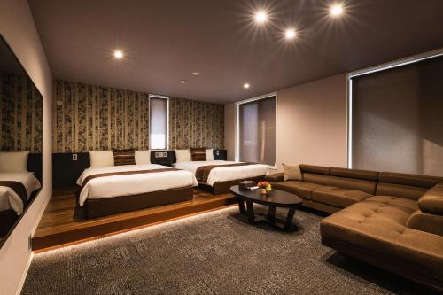 pokój hotelowy z 2 łóżkami i kanapą w obiekcie GRAND BASE Moji Nagomi w mieście Kitakyushu