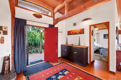 a living room with a red door and a bedroom at Treetop Hideaway - Taupo Holiday Home in Taupo