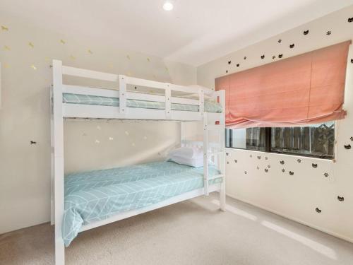 a bedroom with two bunk beds and a window at Mokoia Sunrise - Lakefront Ngongotaha Holiday Home in Ngongotaha