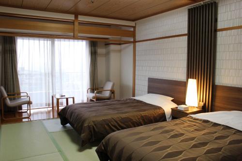 a hotel room with two beds and a window at The Gran Resort Princess Arima in Kobe