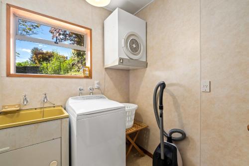 Un pequeño baño con lavadora y lavabo. en Taha Wai - Wanaka Holiday Home, en Wanaka