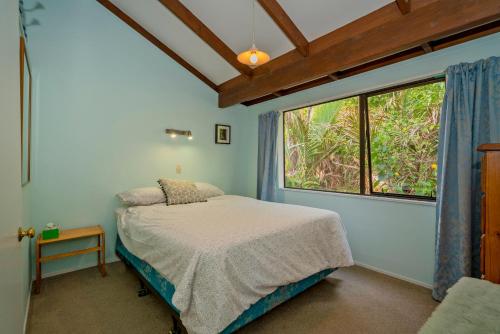 - une chambre avec un lit et une grande fenêtre dans l'établissement Bluebird Bach - Onemana Holiday Home, à Opoutere