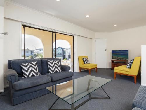 a living room with a couch and a glass table at Sand Castles - Mount Maunganui Holiday Home in Mount Maunganui