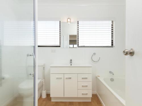 a white bathroom with a sink and a toilet at Sand Castles - Mount Maunganui Holiday Home in Mount Maunganui