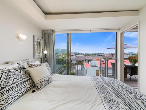 a bedroom with a large bed and a balcony at Relax on Roberts - Taupo Holiday Home in Taupo