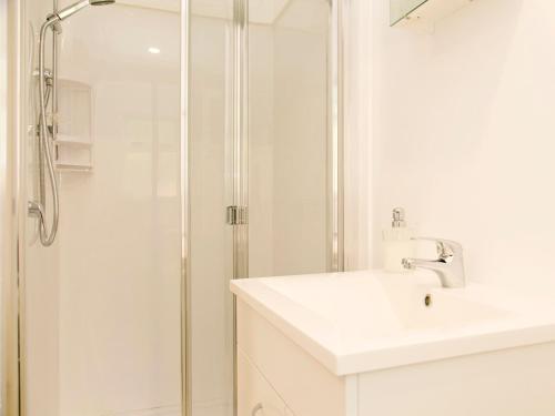 a white bathroom with a shower and a sink at Bellbird Cottage - Lake Taupo Bach in Waitahanui