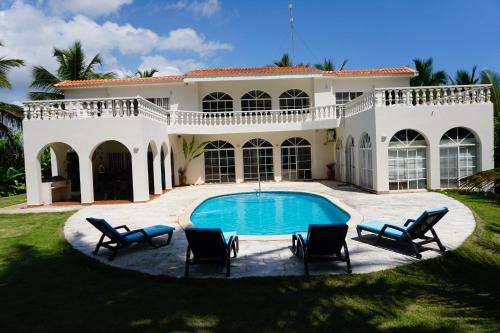 uma grande casa branca com piscina e cadeiras em Baoba Breeze Bed & Breakfast- beachfront paradise em Cabrera