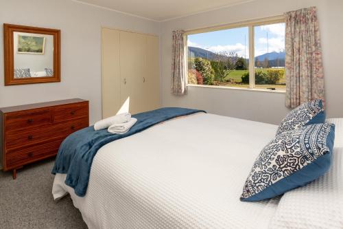 a bedroom with a white bed and a window at Kepler Retreat - Te Anau Holiday Home in Te Anau