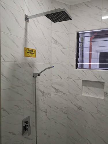a bathroom with a shower with a sign on the wall at Alona Vikings Lodge 2 in Panglao Island