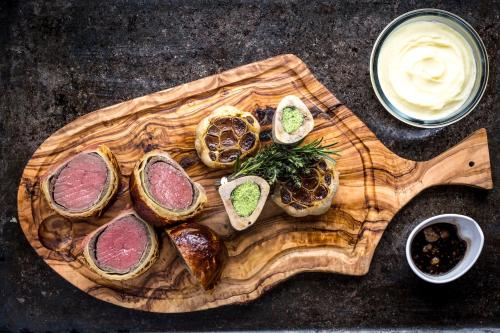 a wooden cutting board with different types of food on it at InterContinental Bordeaux Le Grand Hotel by IHG in Bordeaux